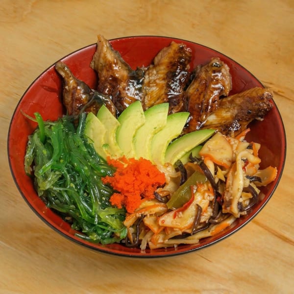 Red bowl filled with eel, avocado, seaweed salad, orange roe, and stir-fried vegetables.