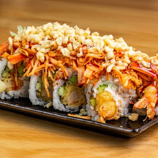 Sushi rolls with tempura shrimp, crab, and crispy toppings, served with pickled ginger.