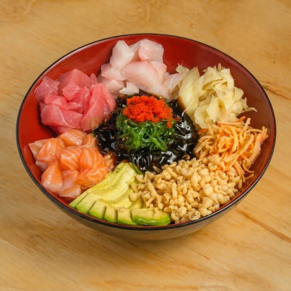 Colorful poke bowl with tuna, salmon, avocado, seaweed, roe, and crispy tempura bits.