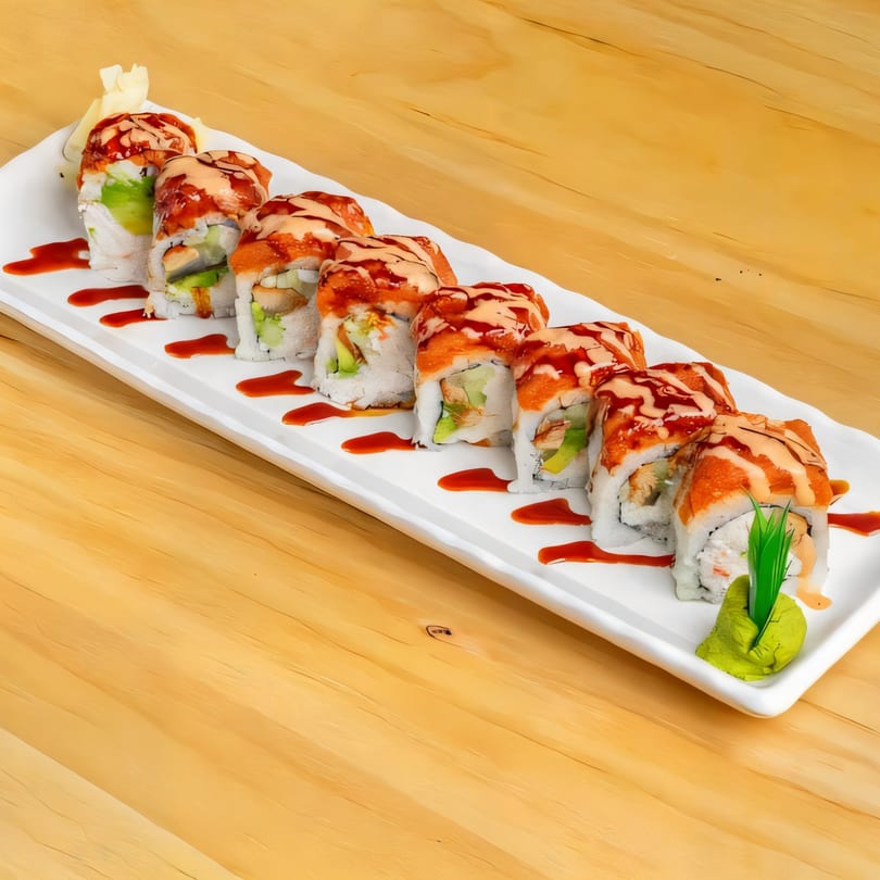 A long white plate of Sushi Go rolls with red and orange sauce, ginger, and wasabi.